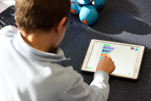 A young boy using an iPad to play with a robot in coding classes for kids