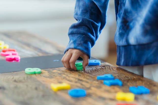 A child engaged in cool math games, playing with vibrant plastic blocks on a table.